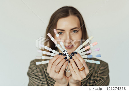 Professional woman master of manicure posing with samples of nails. The nail technician holds the sample palette. Professional woman master of manicure posing with samples of nails. The nail technician holds the sample palette. 101274258