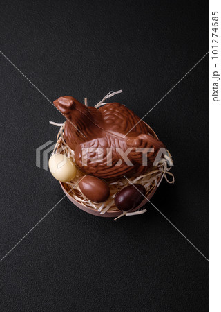 Chocolate Easter hen and eggs in a nest with straw 101274685