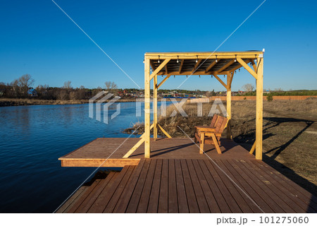 A wooden deck with a bench and a bench on the edge of the water A wooden deck with a bench and a bench on the edge of the water 101275060