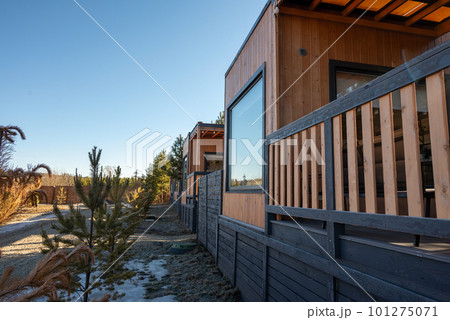 A wooden cabin with a small tree in the foreground and a small tree in the background. 101275071