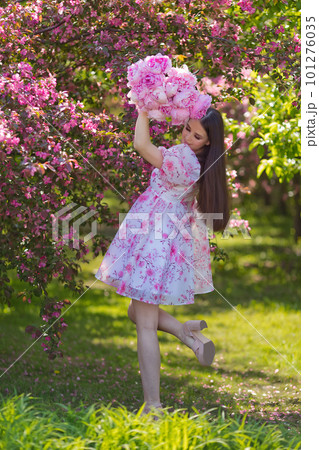 A girl dress, with a bouquet of large pink peonies, stand in blossom A girl dress, with a bouquet of large pink peonies, stand in blossom 101276035