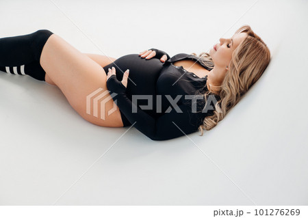 profile a beautiful pregnant in a black bodysuit lies on a cyclorama  101276269
