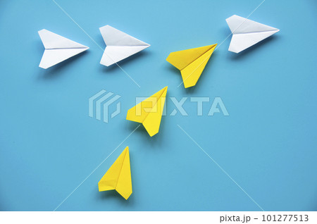 Yellow paper airplane origami joining other white airplanes on blue background with customizable space for text or ideas. Leadership concept and copy space. 101277513