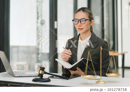 A businesswoman and lawyers are discussing contract papers with a brass scale on a desk in an office. The concepts of law, legal services, advice, justice, and real estate are being discussed. A businesswoman and lawyers are discussing contract papers with a brass scale on a desk in an office. The concepts of law, legal services, advice, justice, and real estate are being discussed. 101278738
