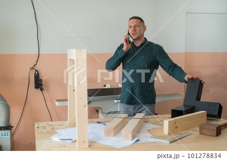 Portrait of a Caucasian man talking on the phone in a workshop. 101278834