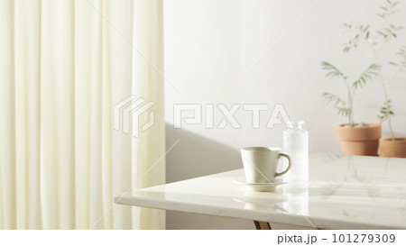 A room with a calm atmosphere, with clay pots placed in front of the wall and curtains letting in natural light. Glass bottles, coffee, and various objects on a marble table 101279309