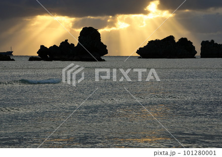沖縄県名護市 名護湾に沈む夕陽からの天使の梯子と海の岩のシルエット 沖縄県名護市 名護湾に沈む夕陽からの天使の梯子と海の岩のシルエット 101280001