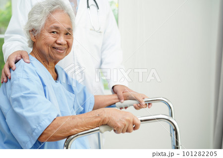 Doctor help Asian elderly woman disability patient walk with walker in nursing hospital, medical concept. 101282205