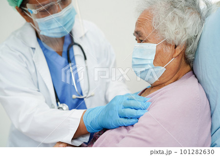 Doctor in ppe user infrared thermometer to check temperature of asian elderly woman patient for safety to protect covid 19 virus. 101282630