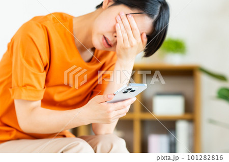 スマホを見て悩む若い女性 101282816