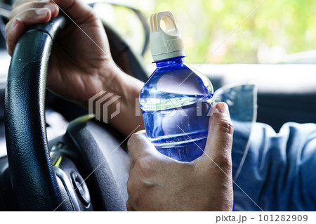 Asian woman driver hold cold water for drink in car, dangerous and risk an accident. Asian woman driver hold cold water for drink in car, dangerous and risk an accident. 101282909