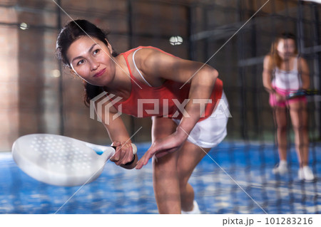 Young asian woman playing padel on a hard court Young asian woman playing padel on a hard court 101283216