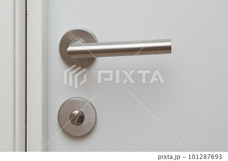 Close-up of a metal door handle in a white door 101287693