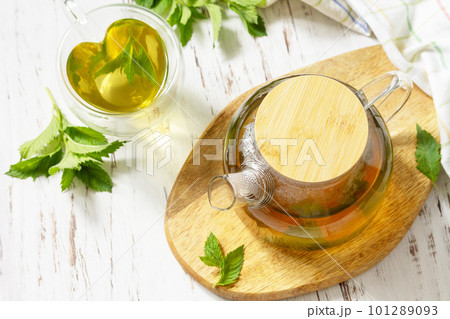 Organic aromatherapy relaxation medical healthy drink. Cup and teapot of fresh natural herbal tea with fresh mint leaves on rustic wooden table. Copy space. 101289093