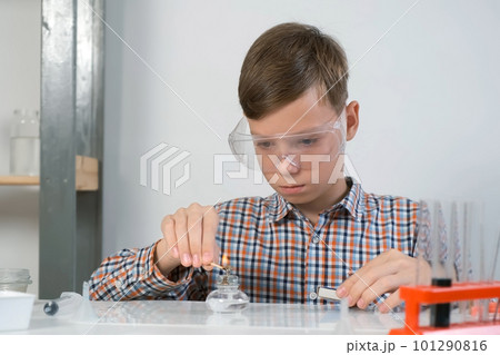 Teen boy sets on fire burning alcohol lamp for chemistry experiments. 101290816