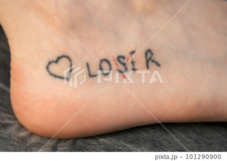 Tattoo with words loser, lover and heart on woman's foot, closeup view. Tattoo with words loser, lover and heart on woman's foot, closeup view. 101290900