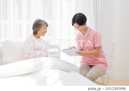 訪問介護 ベットに座るシニア女性から聞き取りをする介護士 訪問介護 ベットに座るシニア女性から聞き取りをする介護士 101290996