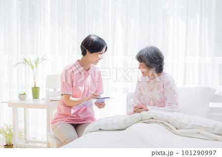 訪問介護　ベットに座るシニア女性から聞き取りをする介護士 101290997