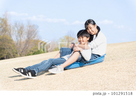 芝すべりをする仲良しの男女 101291518