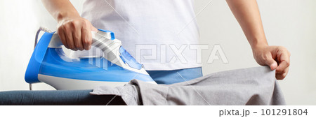 Woman at home electric ironing and pile clothes variety of colors. Woman ironing shirt on ironing board with steaming blue iron. housework and household concept. Woman at home electric ironing and pile clothes variety of colors. Woman ironing shirt on ironing board with steaming blue iron. housework and household concept. 101291804