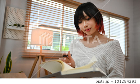 Concentred asian female freelancer reading literature or checking her working schedule plan on diary Concentred asian female freelancer reading literature or checking her working schedule plan on diary 101294293