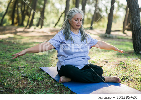 Mature old woman with dreadlocks practicing yoga and tai chi outdoors - wellbeing and wellness 101295420