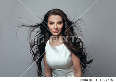 Glamorous healthy brunette model woman with long hairstyle looking at camera on gray background 101295710