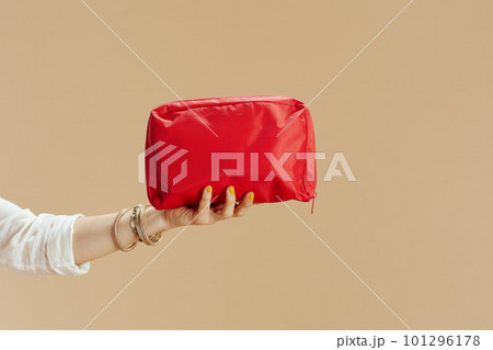 Modern woman in blouse and shorts with firstaid kit on beige 101296178