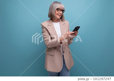 mature woman in a stylish bow chatting on the Internet in a smartphone on a studio background with 101297247