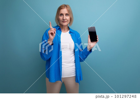 blond middle-aged woman with bob haircut holding smartphone with mocap on studio background blond middle-aged woman with bob haircut holding smartphone with mocap on studio background 101297248