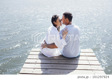 Young couple in love in light casual clothes is sitting on wooden bridge 101297924