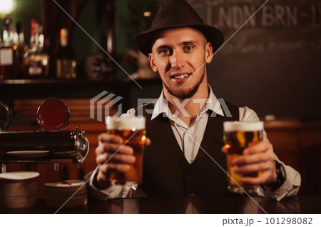 happy bartender serves two glasses of light draft beer lager with foam in hand at bar 101298082