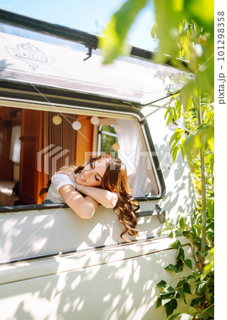 Beautiful stylish bride near trailer. Camping season. Marriage. Happy newlywed woman. 101298358