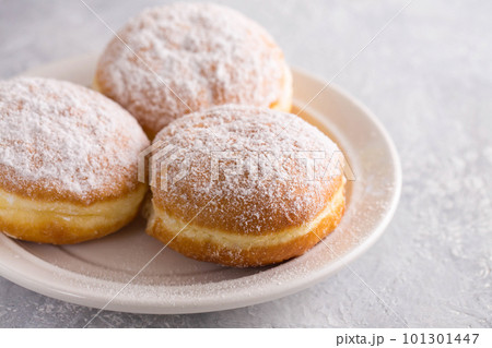 Ruddy delicious donuts berliners with filling sprinkled with powdered sugar on a white plate 101301447