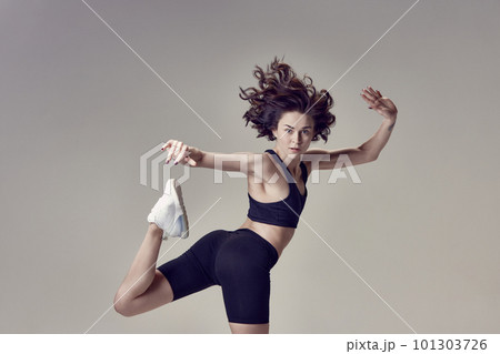 Dynamic postural training. Young beautiful woman in sportswear training, posing in motion against grey studio background 101303726