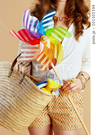 Elegant woman in blouse and shorts with windmill toy on beige Elegant woman in blouse and shorts with windmill toy on beige 101305394