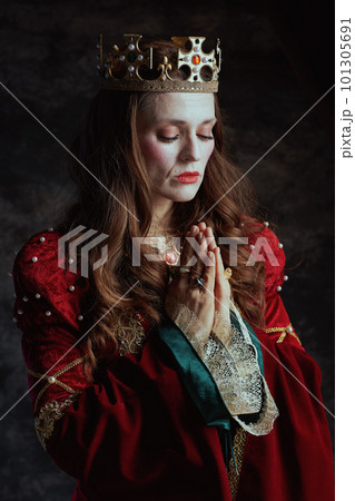 medieval queen in red dress with crown praying 101305691