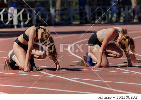 two female athletes low start running 100 meters in track stadium, summer athletics championship 101306232