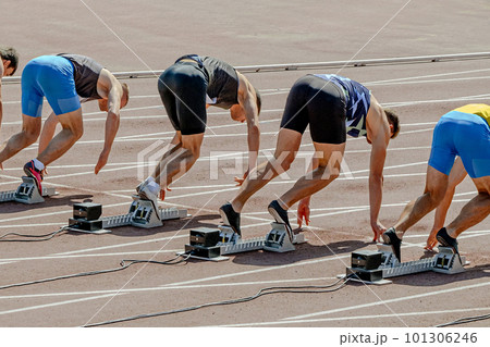 group sprinter runners in starting position ready, 100 - meter race in summer athletics championships group sprinter runners in starting position ready, 100 - meter race in summer athletics championships 101306246