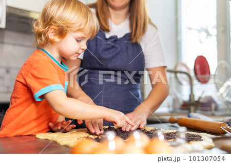 Mother and son boy making cookies and having fun in the kitchen Mother and son boy making cookies and having fun in the kitchen 101307054