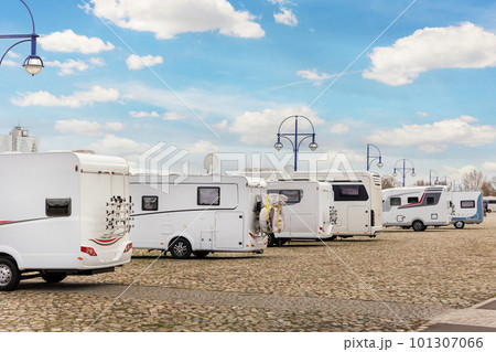 Many white modern campervan recreational motor home vehicles parked in row at camper park site Magdeburg city against Elbe river bridge. Motorhome campground stataion travel destination. RV lifestyle Many white modern campervan recreational motor home vehicles parked in row at camper park site Magdeburg city against Elbe river bridge. Motorhome campground stataion travel destination. RV lifestyle 101307066