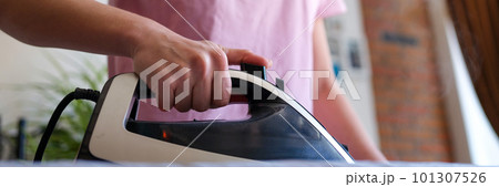 Cheerful happy housewife irons clothes on ironing board Cheerful happy housewife irons clothes on ironing board 101307526