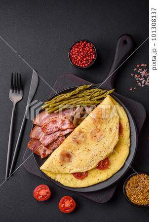 Delicious fresh omelet with cherry tomatoes, bacon, asparagus and spices 101308137