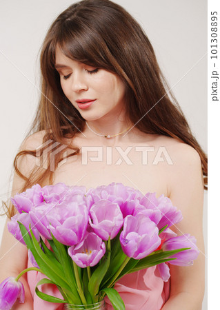 portrait of a woman topless with a bouquet of tulips on a white background. 101308895
