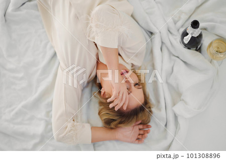top view. blonde in delicate pajamas in bed with a champagne top view. blonde in delicate pajamas in bed with a champagne 101308896