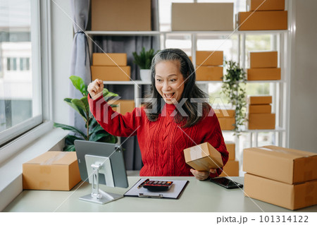 Senior business owner woman prepare parcel box and standing check online orders for deliver to customer on tablet, laptop Shopping Online concept. at home office. Senior business owner woman prepare parcel box and standing check online orders for deliver to customer on tablet, laptop Shopping Online concept. at home office. 101314122