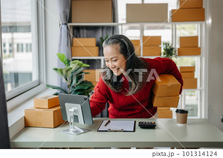 Senior business owner woman prepare parcel box and standing check online orders for deliver to customer on tablet, laptop Shopping Online concept. at home office. Senior business owner woman prepare parcel box and standing check online orders for deliver to customer on tablet, laptop Shopping Online concept. at home office. 101314124