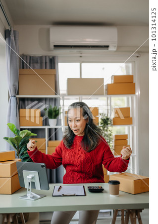 Senior business owner woman prepare parcel box and standing check online orders for deliver to customer on tablet, laptop Shopping Online concept. at home office. 101314125