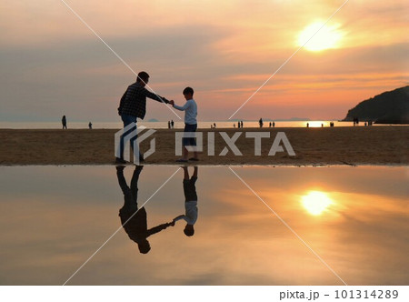 夕焼けの浜辺でグーのパンチのまねをする父親と息子 101314289
