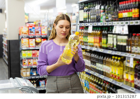Smiling young woman choosing the different oil in the modern supermarket 101315287